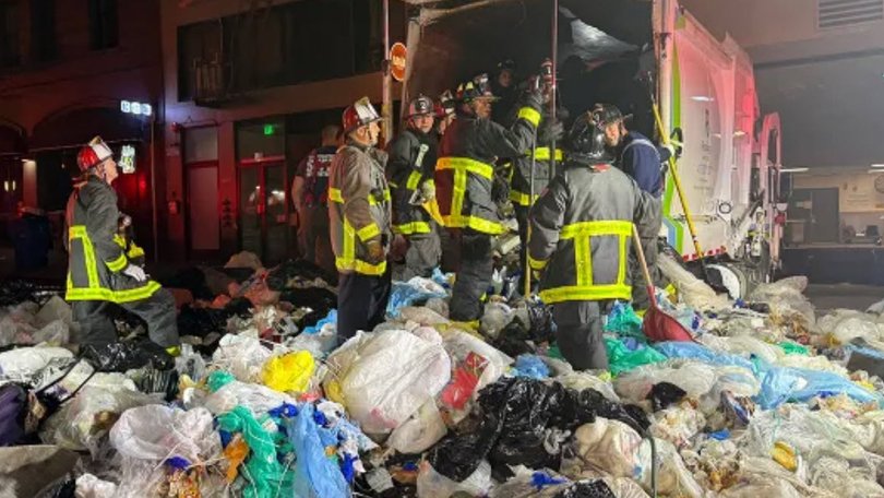 Emergency services were in a race against the clock to save a man who was trapped inside a garbage truck under a pile of waste in on Wednesday morning.