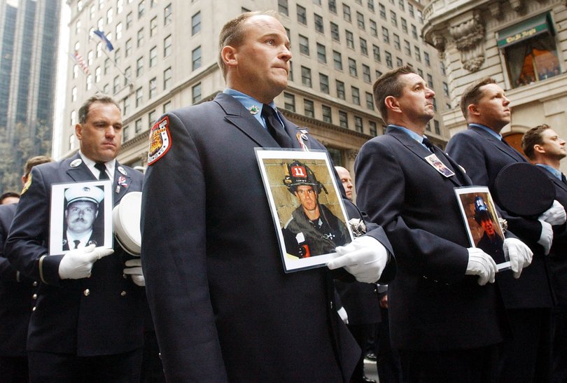 New York City firefighter Mike Heffernan (C) of Engine Company 13, holds a photo of his brother John, of Ladder Company 11, who was killed in the September 11 terrorist attacks, during a pause to honor those who lost their life in attacks World Trade Center, 16 March 2002 during the annual St. Patrick's Day Parade on New York's Fifth Avenue. AFP PHOTO Henny Ray ABRAMS (Photo by HENNY RAY ABRAMS / AFP)