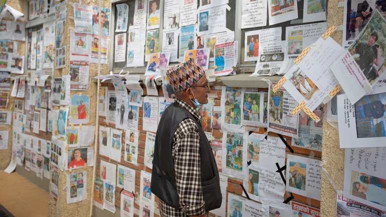A man looks at a wall covered with photographs of people reported missing after the deadly floods in the Himalayan valley.