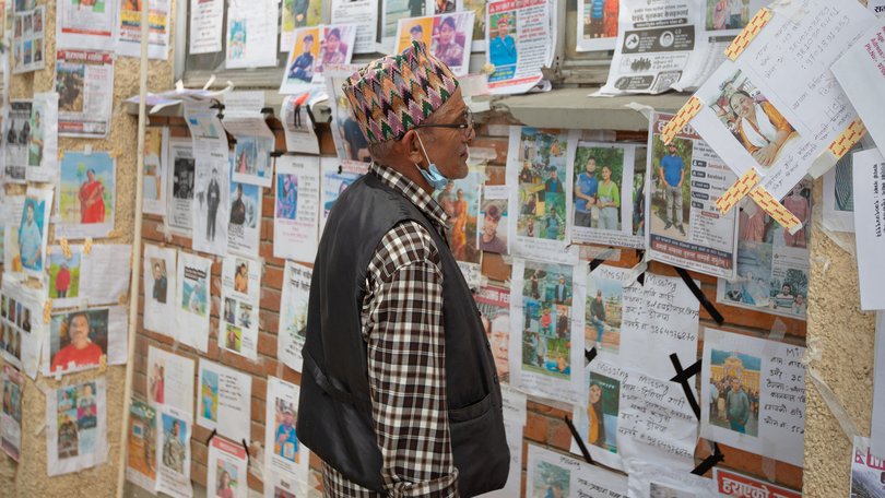 A man looks at a wall covered with photographs of people reported missing after the deadly floods in the Himalayan valley.