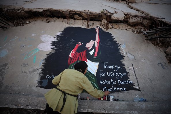 Palestinian artists put the finishing touches on a mural depicting American rapper Macklemore on the ruins of homes destroyed by the Israeli army in Gaza City