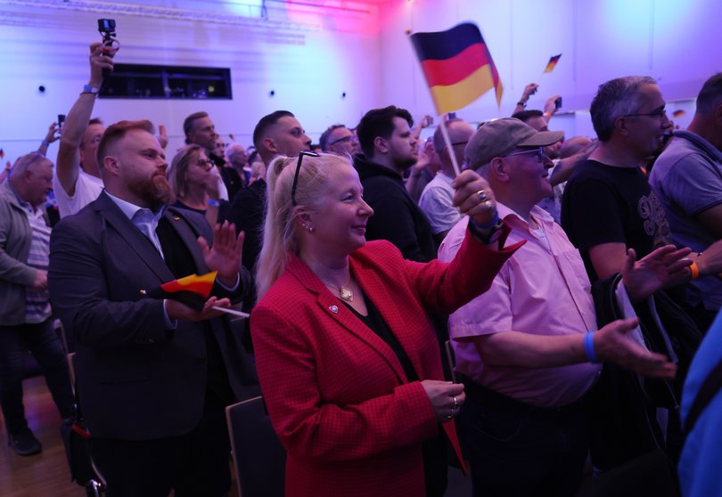 Supporters of the far-right Alternative for Germany (AfD) applaud and hold German flags as they attend an election campaign rally ahead of state elections.