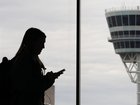 A traveler with a smartphone walks past an air traffic control tower at Philadelphia International Airport.