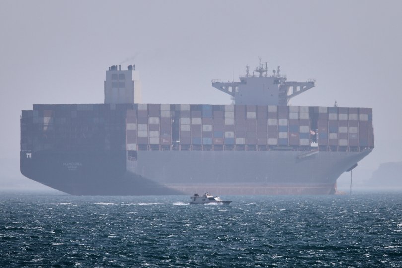 A container ship sits at anchor as a small motorboat passes in the foreground in the Strait of Hormuz off Bandar Abbas, Iran, Saturday, May 2, 2026.