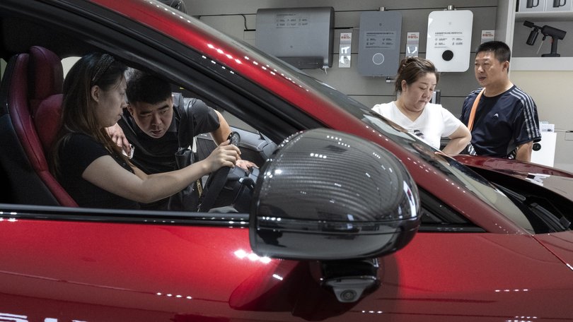 Prospective buyers check a Xiaomi electric car in Beijing on Sept. 10. (Gilles Sabrié/For The Washington Post)