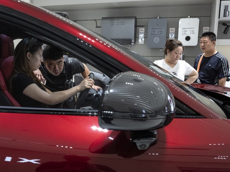 Prospective buyers check a Xiaomi electric car in Beijing on Sept. 10. (Gilles Sabrié/For The Washington Post)
