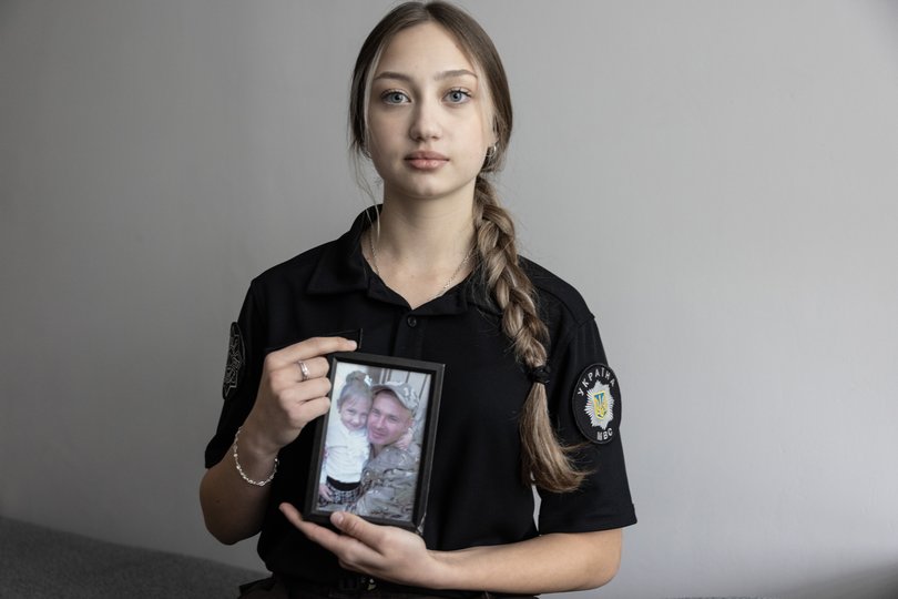 Uliana, 15, holds a photograph of her father hugging her as a child.