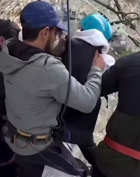 Footage shows an operator kicking the woman's legs as she stands on the platform.