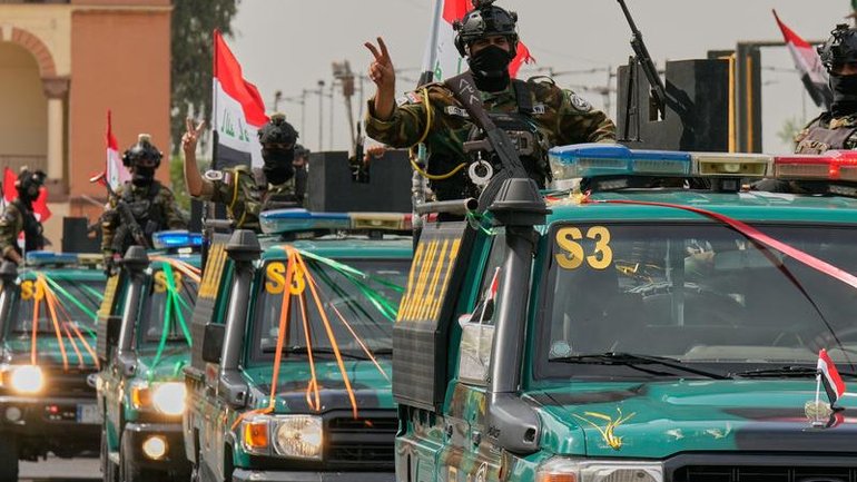 Iraqi security officers flash victory signs during a convoy celebrating the US's full withdrawal.