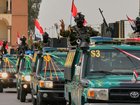 Iraqi security officers flash victory signs during a convoy celebrating the US's full withdrawal.