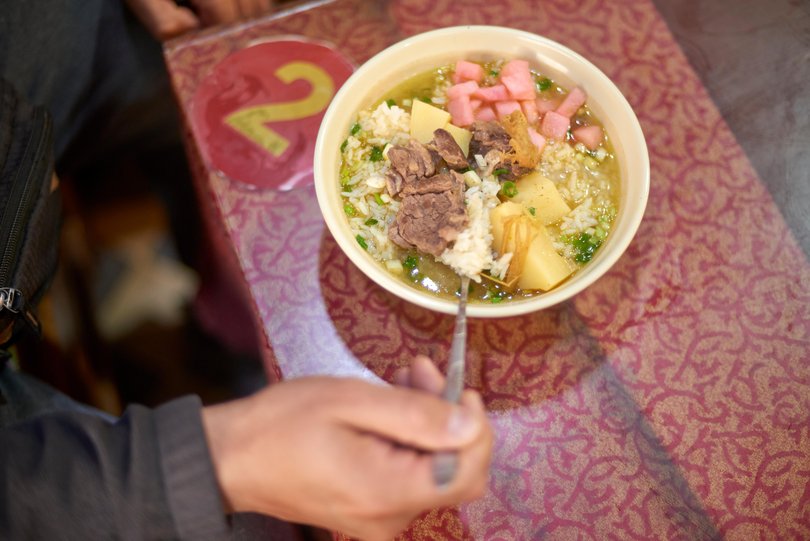 A hearty bowl of traditional tibetan yak meat soup with rice, potatoes and vegetables in a cozy lhasa restaurant.