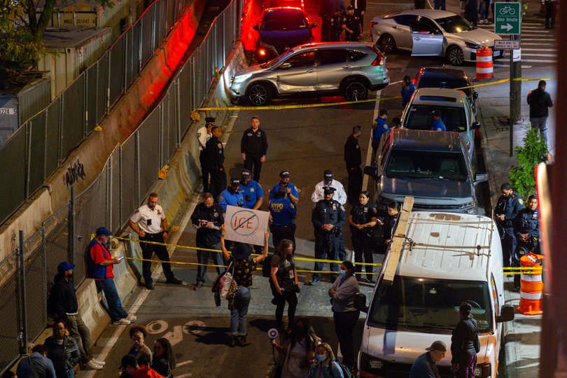 A protester holds up an anti-ICE sign near the scene where a federal immigration agent shot a man in the Marble Hill neighborhood of New York City.