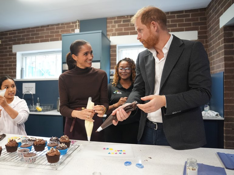 Meghan, Duchess of Sussex and Prince Harry, Duke of Sussex decorate cupcakes at Epic Partners.