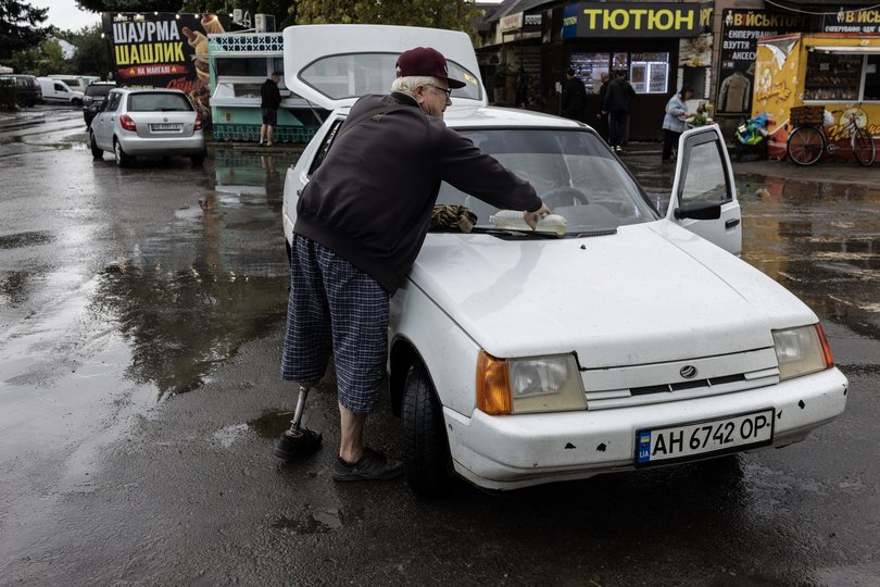 An elderly man with an amputated leg cleans off his windshield in Ukraine’s Donetsk region.