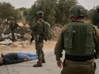 Israeli soldiers stand beside a Palestinian man after soldiers shot him following a settler attack. (AP PHOTO)