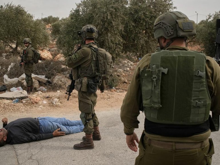 Israeli soldiers stand beside a Palestinian man after soldiers shot him following a settler attack. (AP PHOTO)