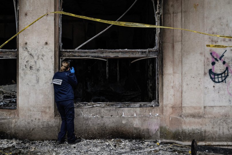 A forensic officer examines the burnt Lyon Office de Tourisme a day after riot and looting.