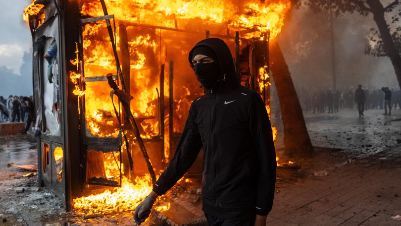 A protester walks past a burning news-stand during demonstrations in Paris, France.