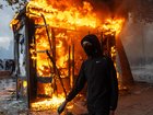 A protester walks past a burning news-stand during demonstrations in Paris, France. 