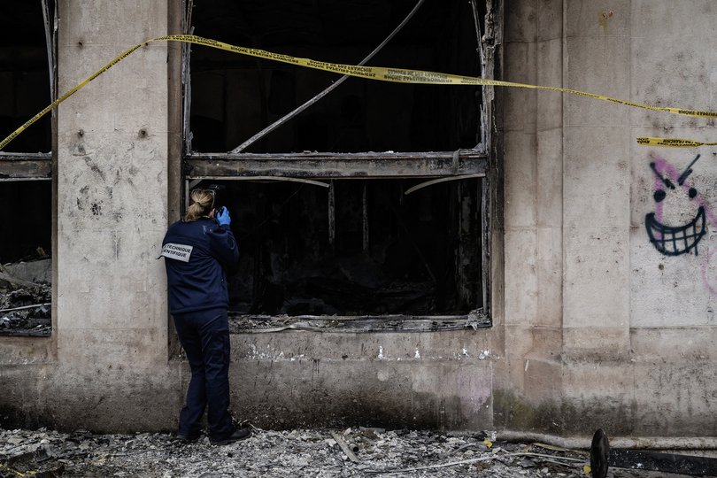 A forensic officer examines the burnt Lyon Office de Tourisme a day after the riots.