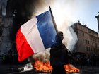 A protester waving a French national flag walks past a fire during clashes prior to the start of a demonstration in Marseille, southern France.