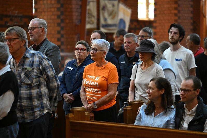 People line up to light candles during a vigil for independent federal MP Helen Haines