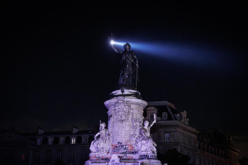 A helicopter patrols over the Statue de la République at Place de la Republique during a partial curfew in Paris.