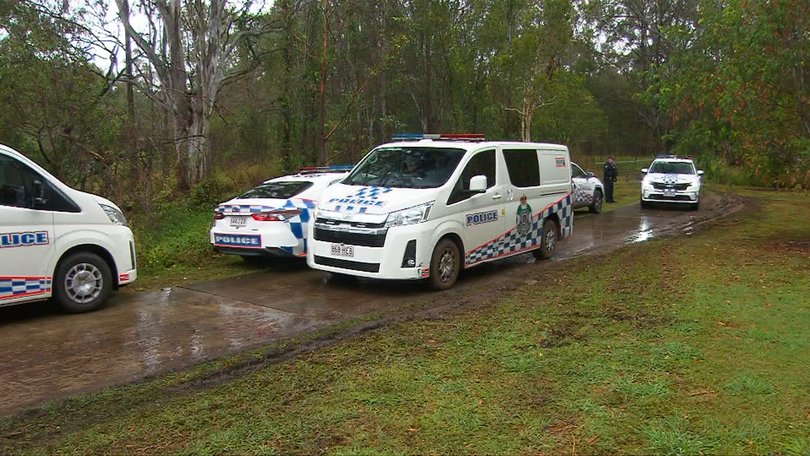 Police vehicles line a bushland track in Chermside, where a 48-year-old man’s body was discovered near the scene of a dog attack.