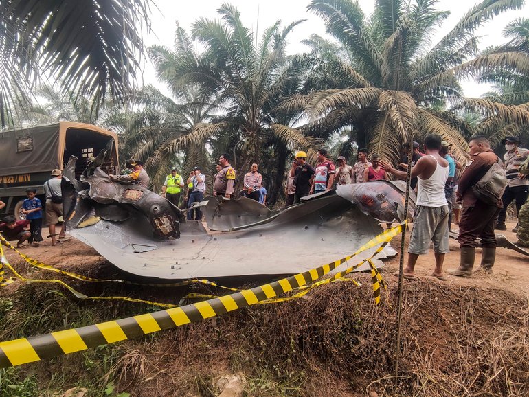 Residents, plantation workers, and security officials gather around a large charred metallic fragment, suspected to be rocket debris, at an oil palm plantation in East Kotawaringin Regency, in Indonesia's Central Kalimantan province. Indonesian authorities were investigating  after a piece of rocket the size of a car crashed into an oil palm plantation on Indonesian Borneo. 