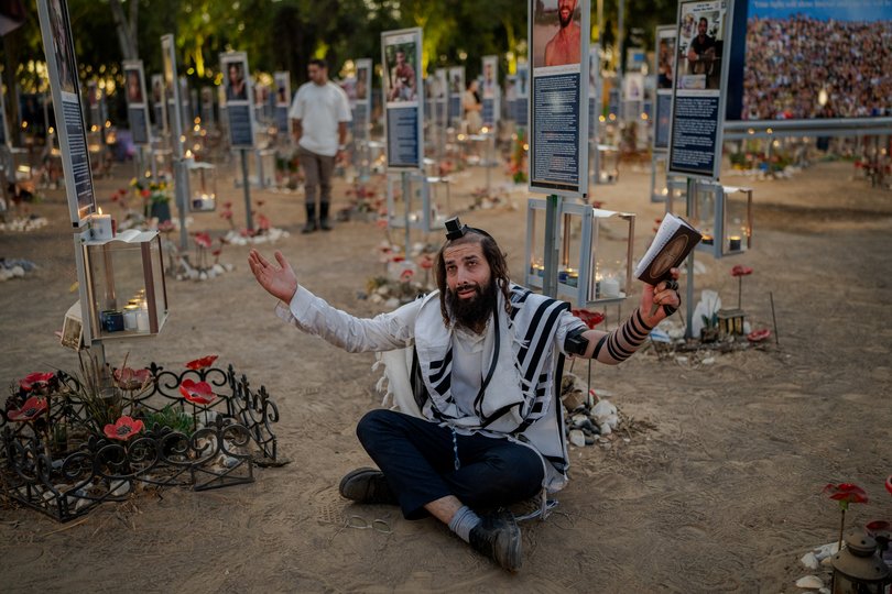 A man prays beside memorial markers at the Nova music festival site as Israel marks the third anniversary of the Oct. 7th 2023 attack.