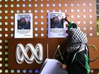 A woman places photos of Palestinian photojournalist Roshdi Sarraj during a vigil for journalists killed in Gaza outside the ABC Melbourne offices in Melbourne, Tuesday, October 31, 2023. (AAP Image/Joel Carrett) NO ARCHIVING